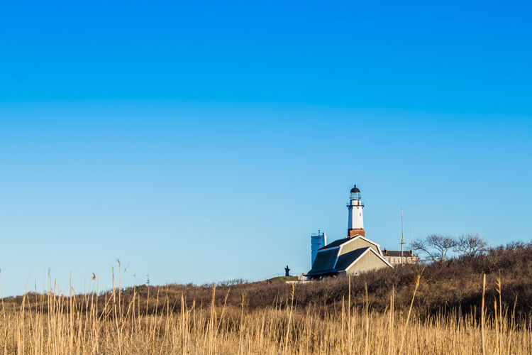 Lighthouse on field against clear blue sky