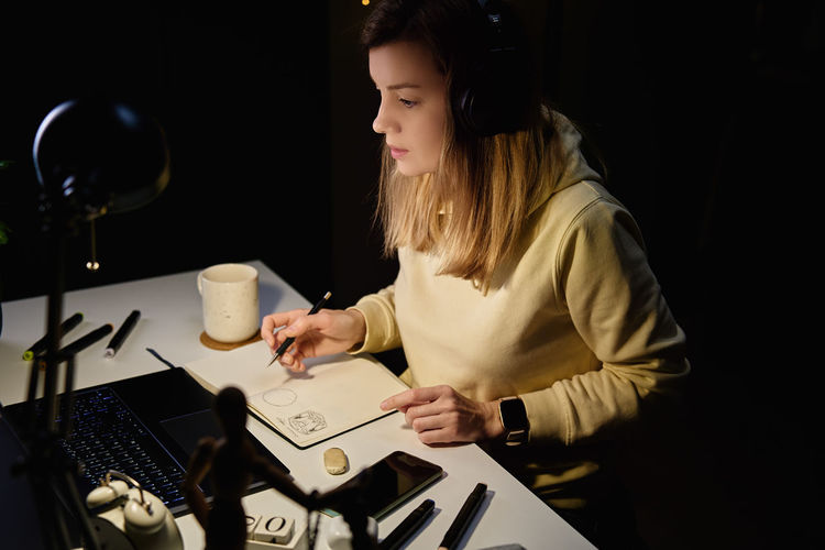 Female designer working in home office at night