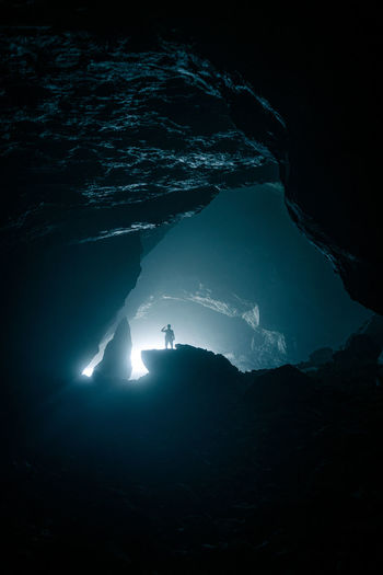Silhouette of man on rock in cave