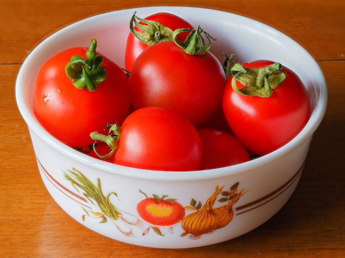 Freshly picked bright red home grown tomatoes, variety mountain magic, in a small bowl