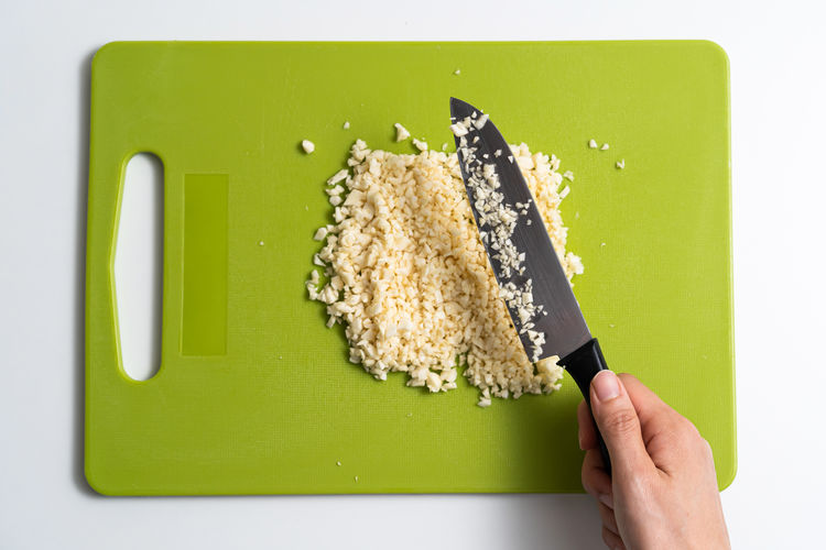 Directly above shot of person holding leaf on cutting board