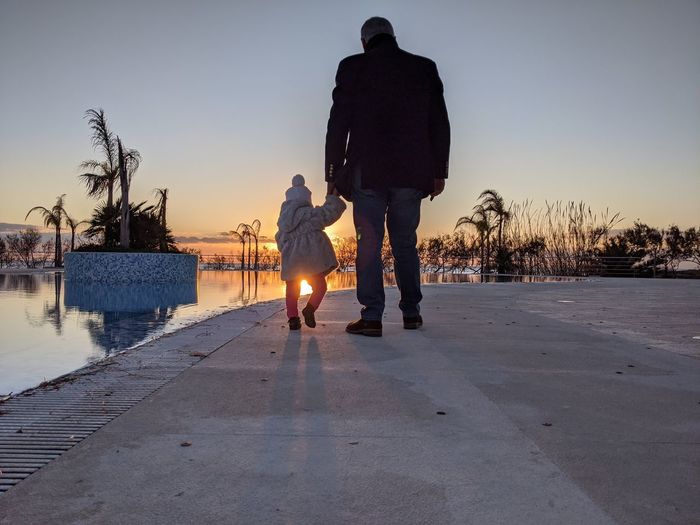 Rear view of father with daughter during sunset