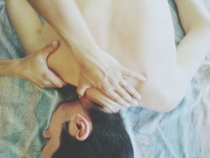 Cropped hands of massage therapist massaging shirtless male customer