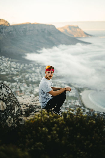 Man sitting on rock against mountain