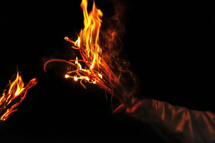 Pictures of hand-holding flaming torches in the dark night, burning. 