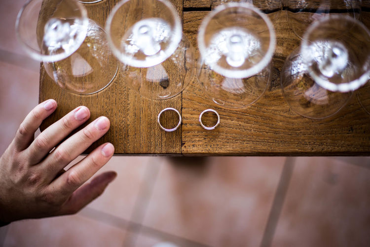 Cropped hand of man by wineglasses and rings on table