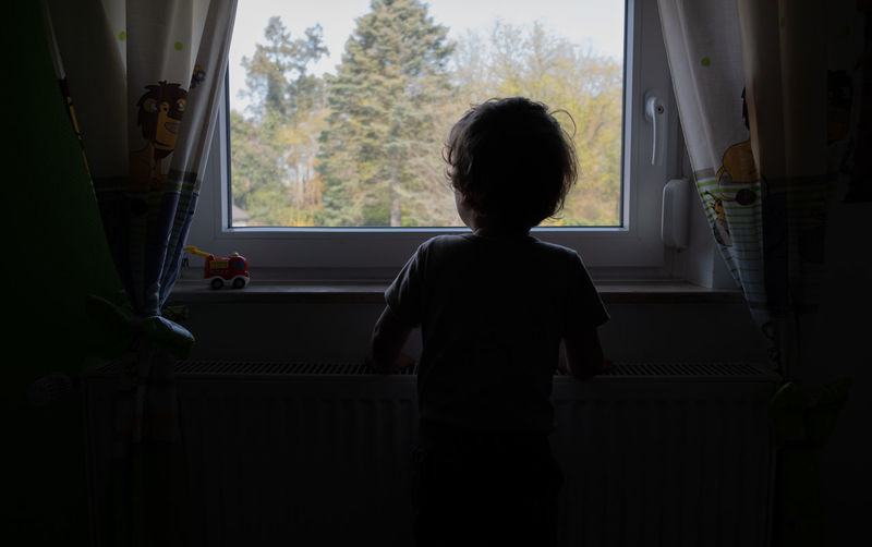 Little boy standing at the window 