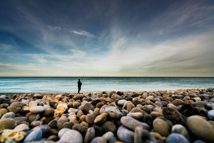 Man fishing on shore at beach