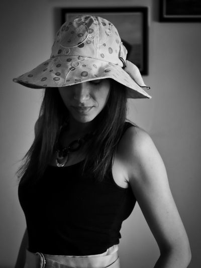 Portrait of woman wearing hat standing against wall