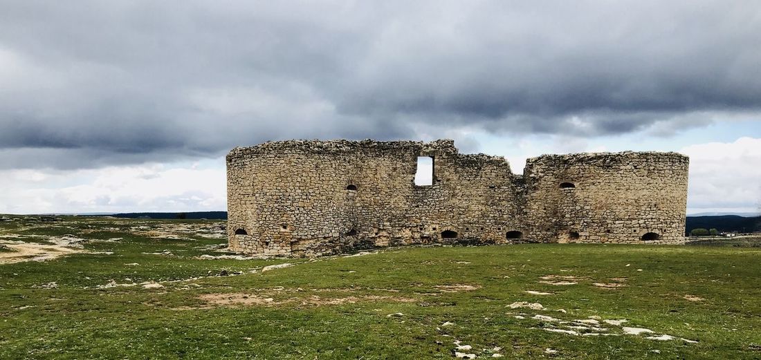 Old ruin building on field against cloudy sky