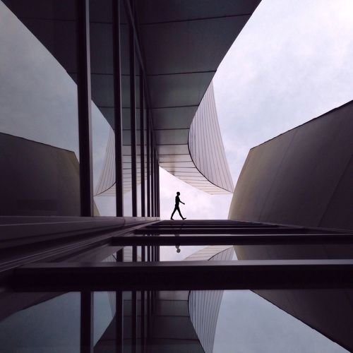 Silhouette person walking outside modern building