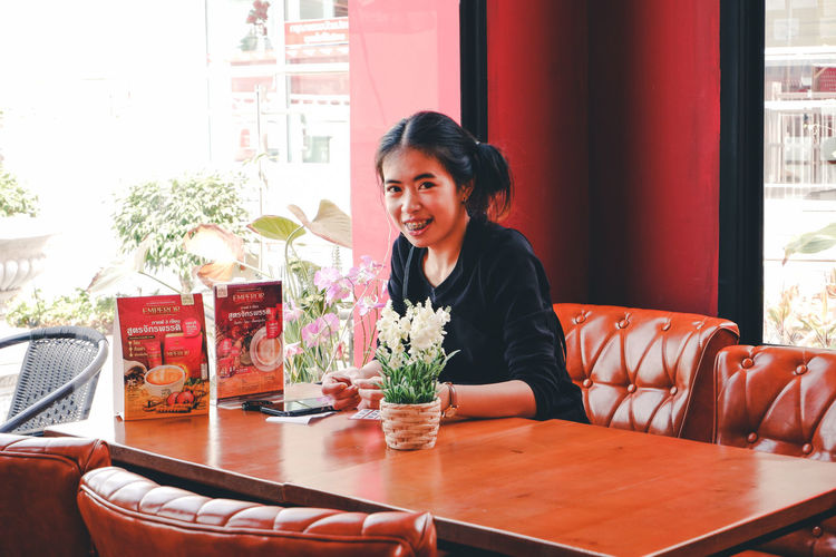 Portrait of woman sitting on table in restaurant
