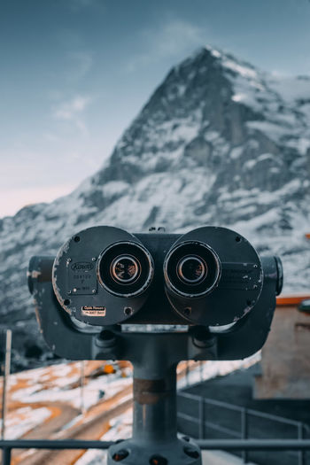 Close-up of coin-operated binoculars against snowcapped mountain
