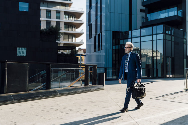 Senior businessman with briefcase walking outside building exterior