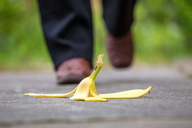 A pedestrian and a banana peel are on a walkway
