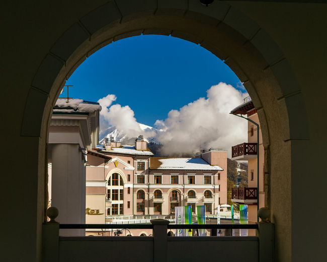 Low angle view of buildings against sky seen through window