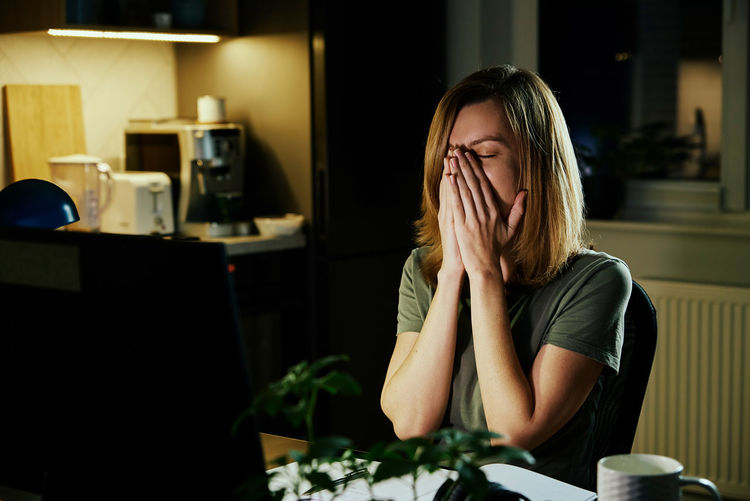 Tired woman works at home workplace