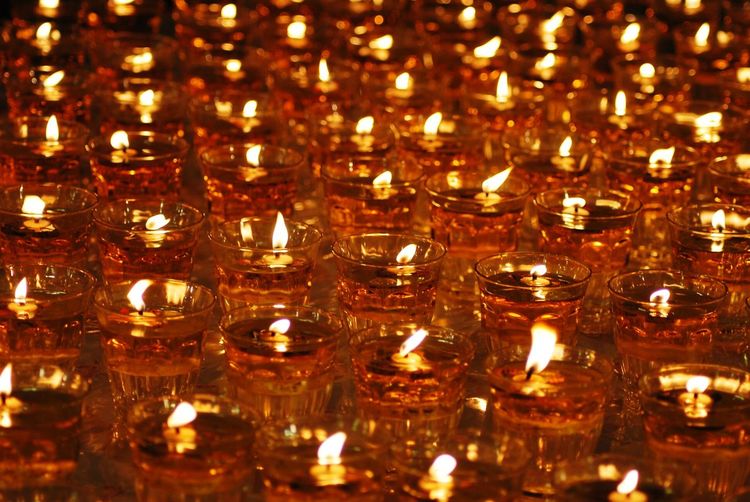 Close-up of lit diyas in glass containers at night during festival