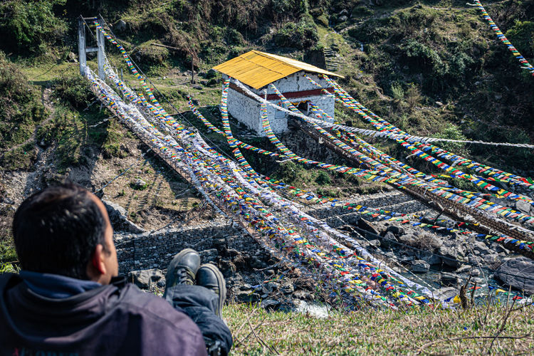 Man watching ancient holy iron bridge with many buddhist holy flags from top angle 