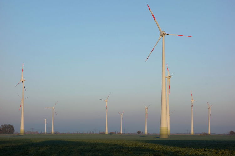Low angle view of windmills on field against clear sky