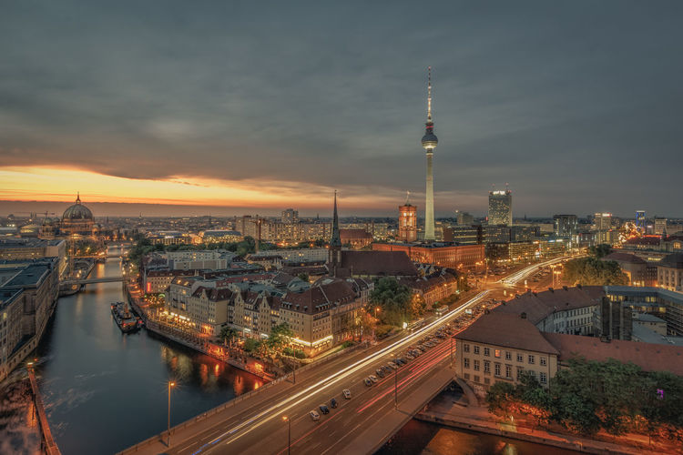 Illuminated cityscape against sky during sunset