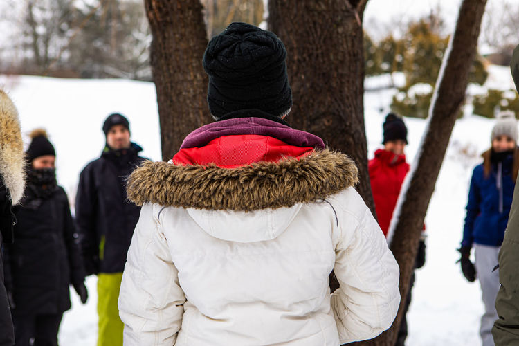 Rear view of woman standing by tree during winter