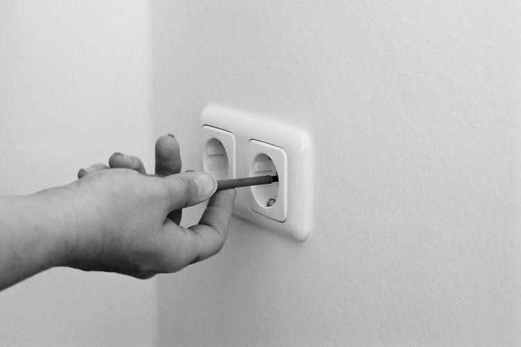 Cropped image of electrician repairing electrical outlet on wall