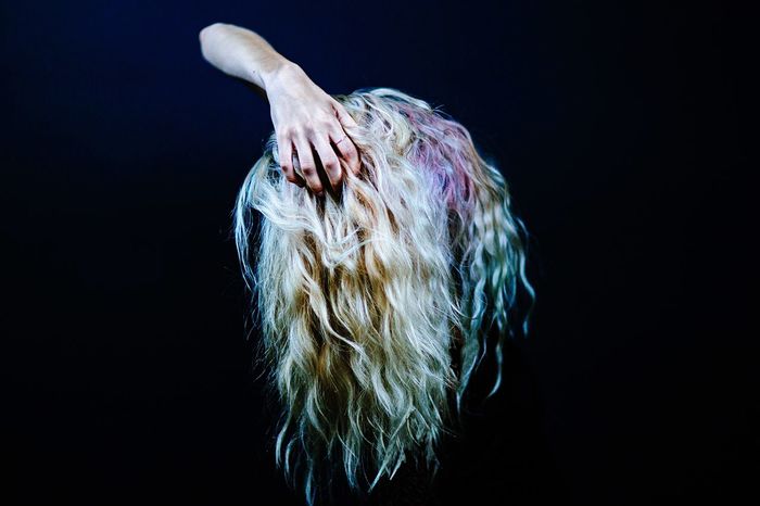 Digital composite image of hand holding blond hair against black background