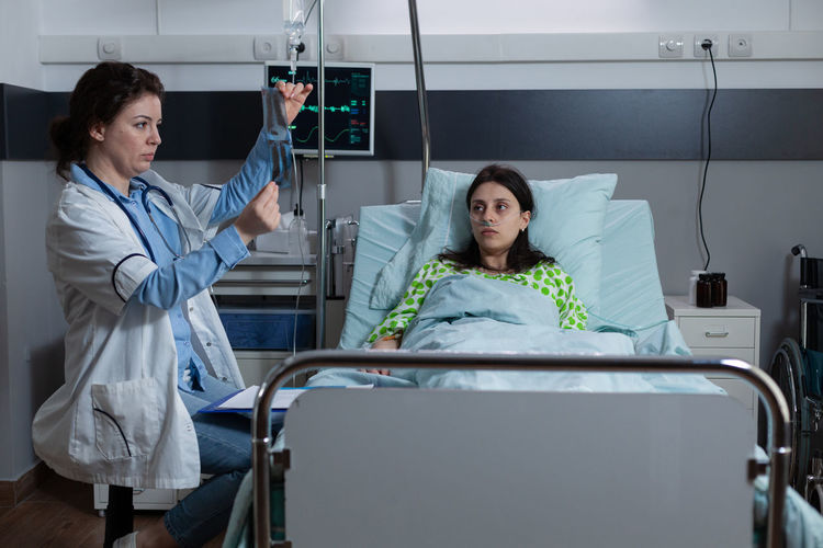 Portrait of young woman using mobile phone while standing in hospital