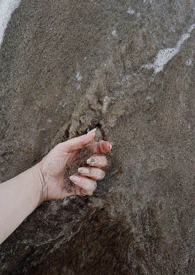 High angle view of hand on sand at beach