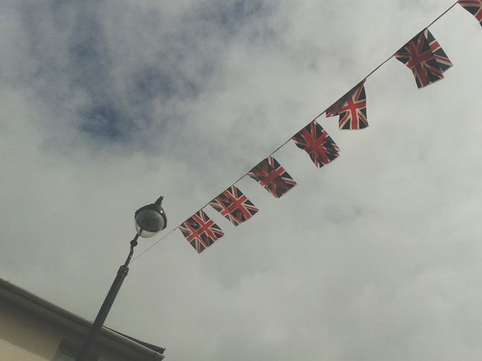 Low angle view of british flags hanging from street light against sky