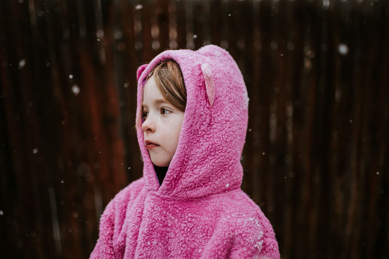 Side view of young girl looking away with a hooded sweatshirt on