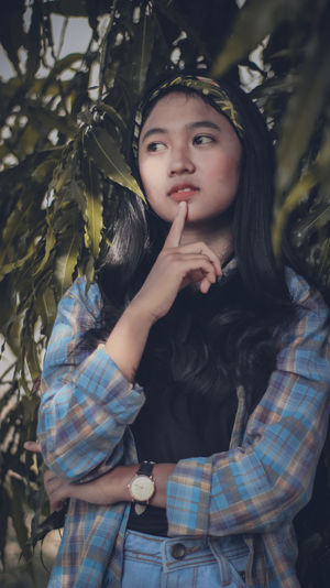 Woman looking away while standing by plants