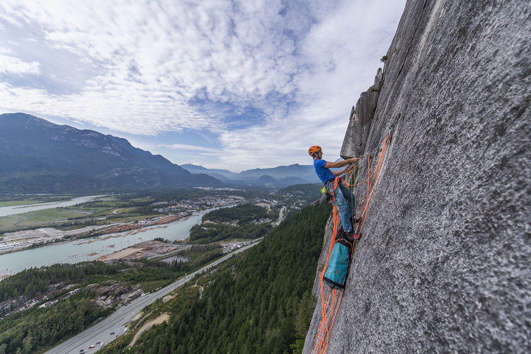 Man hauling haul bag while rock climbing on granite with view squamish