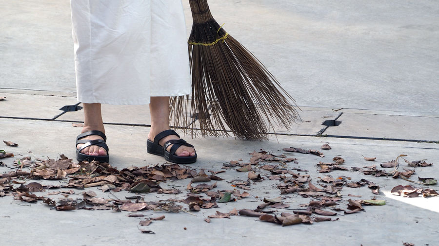 Low section of woman sweeping up leaves