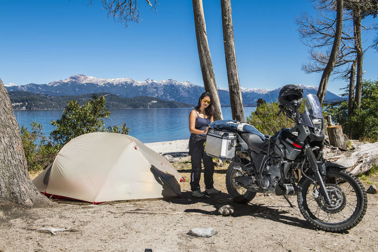 Woman packing motorbike at camp at the nahuel huapi lake in patagonia