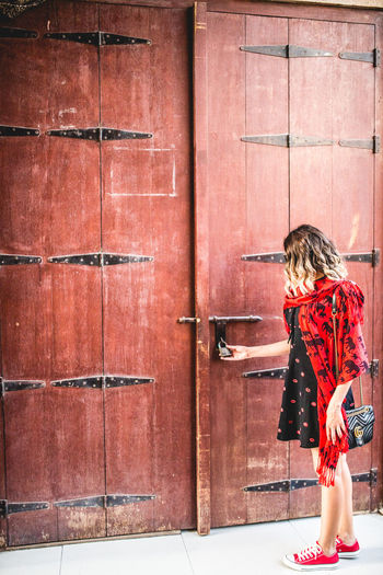 Side view of woman standing against door