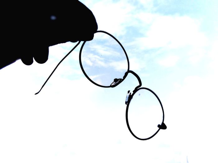Low angle view of silhouette eyeglasses against sky