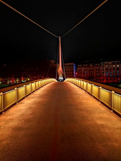 Illuminated footbridge against sky at night