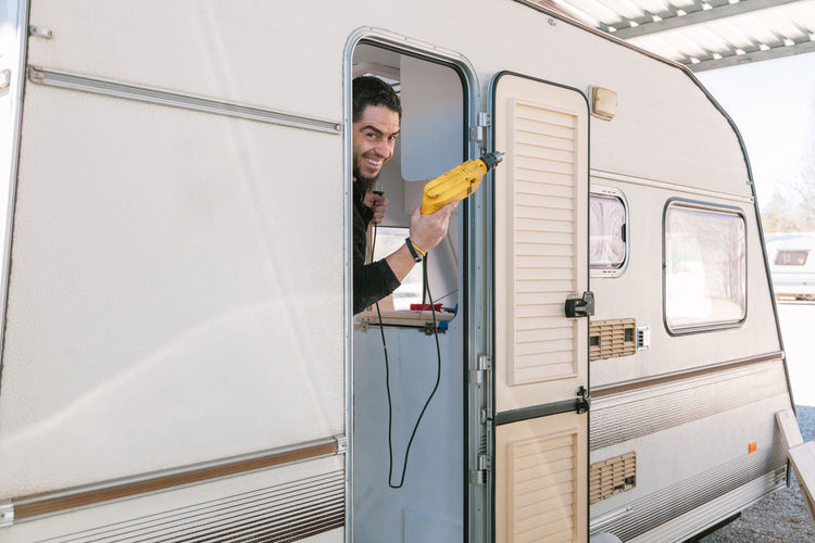 Portrait of smiling man holding drill in camper trailer