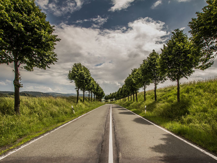 Road amidst trees against sky