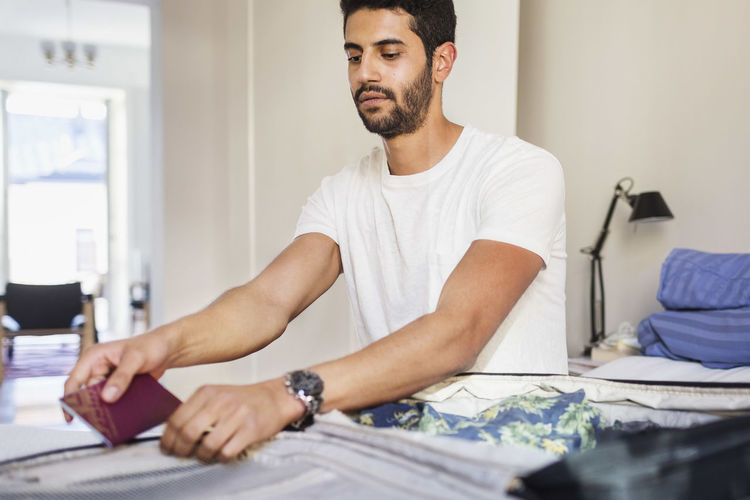 Man packing for vacation in bedroom