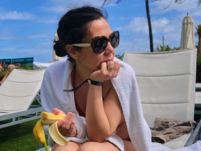 Young woman in glasses sitting near a pool at the resort