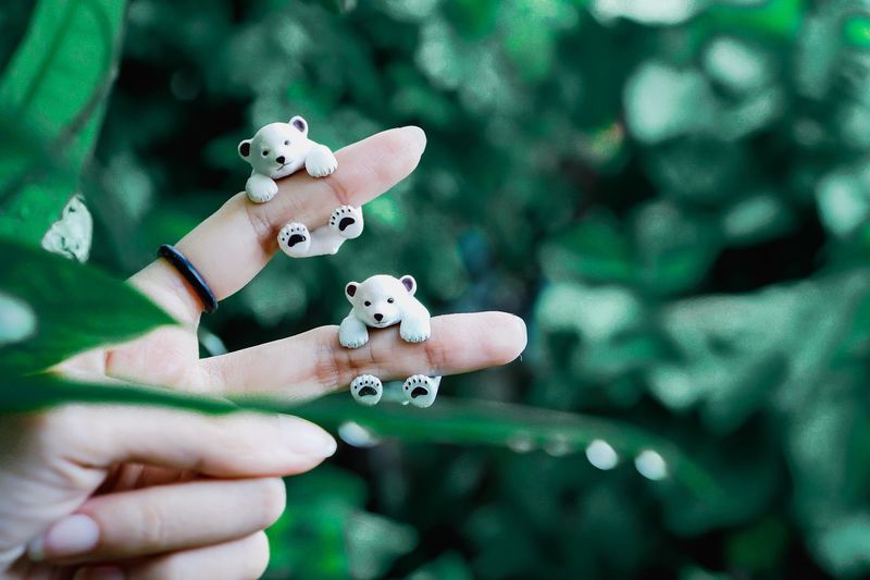 Cropped hand with toy animals against plants