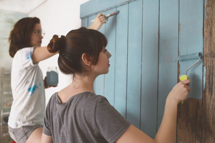 Young friends painting door in blue