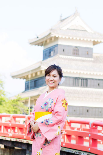 Portrait of smiling woman standing against temple in city