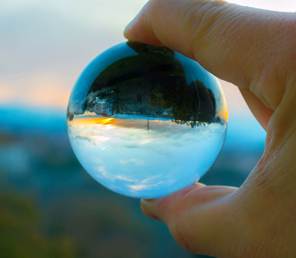 Close-up of hand holding crystal ball with reflection