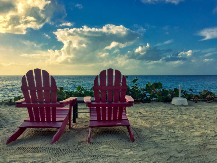 Chairs on beach against sky