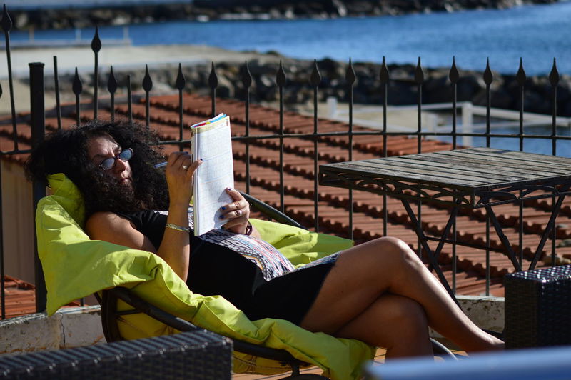 Pregnant woman reading book at beach