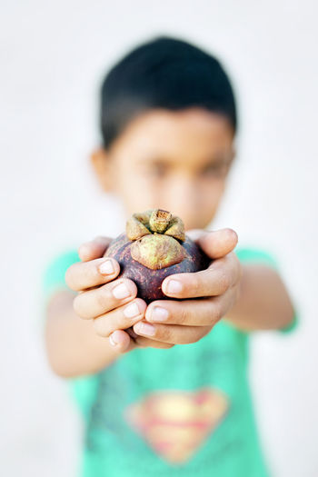 Close-up of boy holding fruit over white background